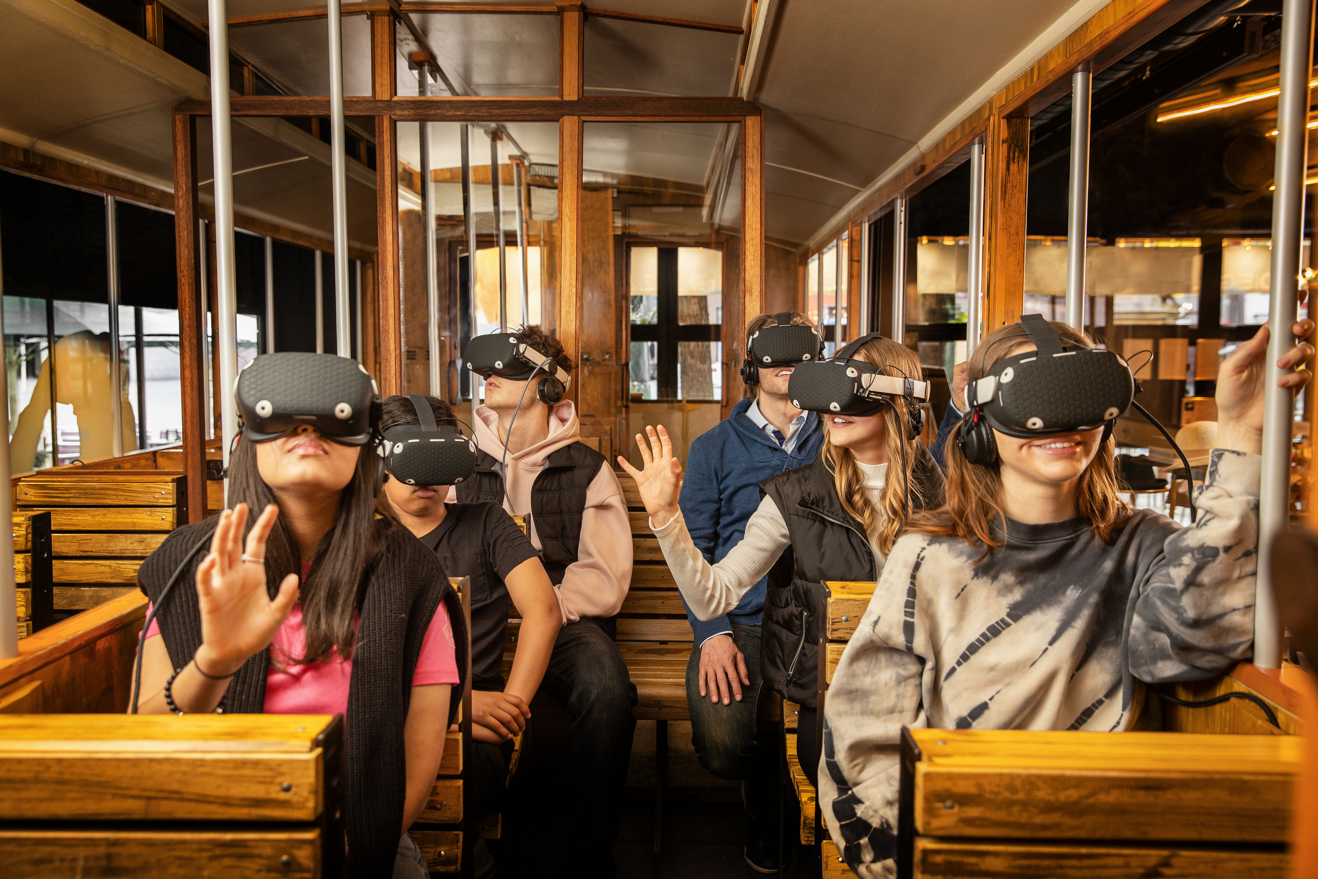 Schulklasse in alter Tram, die VR-Brille auf dem Kopf trägt