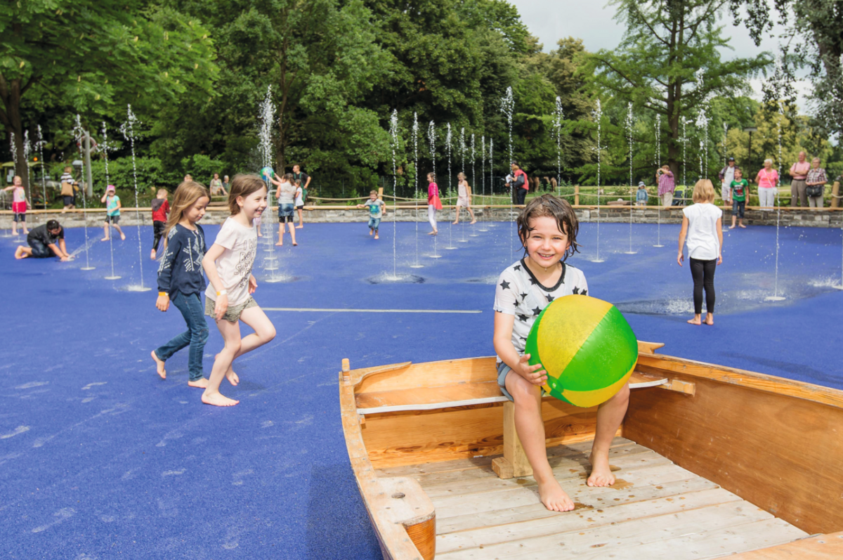 Ein Kind sitzt mit einem Wasserball in einem Boot auf dem großen Wasserspielplatz im Tierpark Berlin