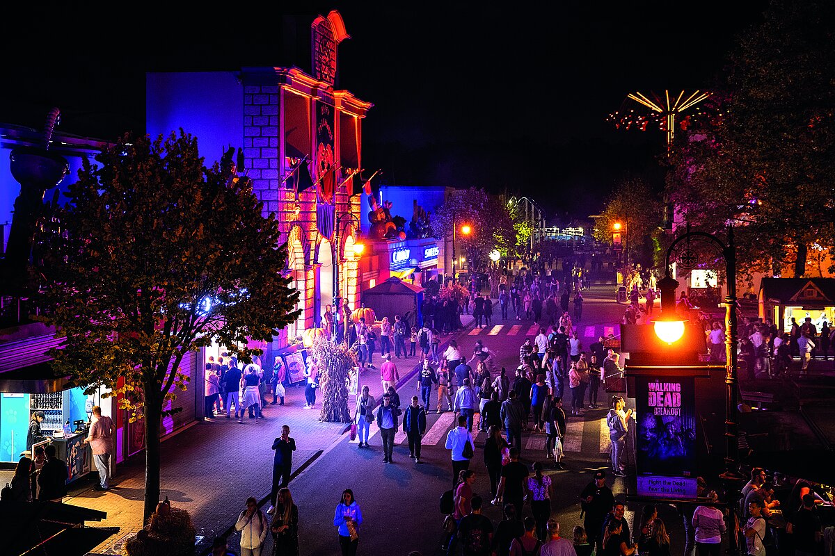 Der Horrorwood Boulevard beim Halloween Horror Festival aus der Luft aufgenommen. Menschen flanieren zwischen kostümierten Erschreckern.
