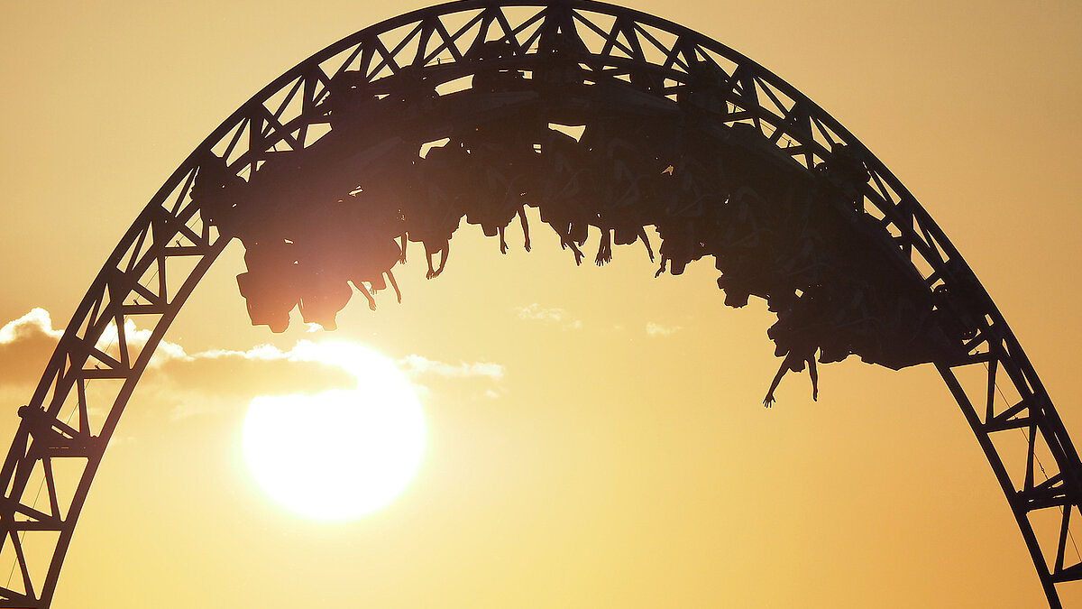 Eine Achterbahn fährt einen Looping vor untergehender Sonne