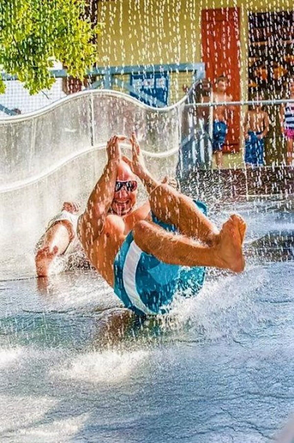 Ein Mann rutsch auf einer mit Wasser bedeckten Plastikbahn