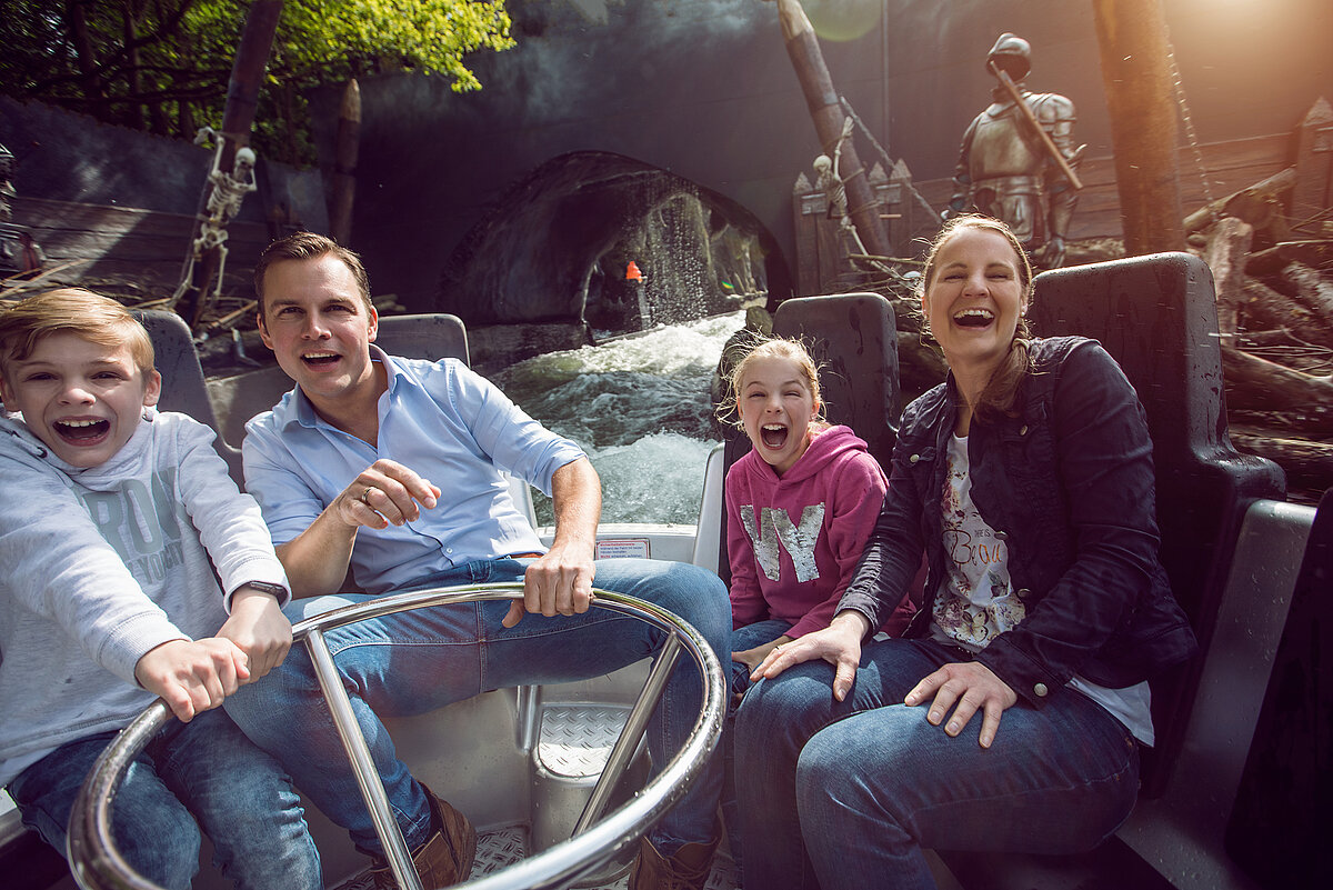 Eine Familie sitzt freudig im Wagon einer Wasserbahn