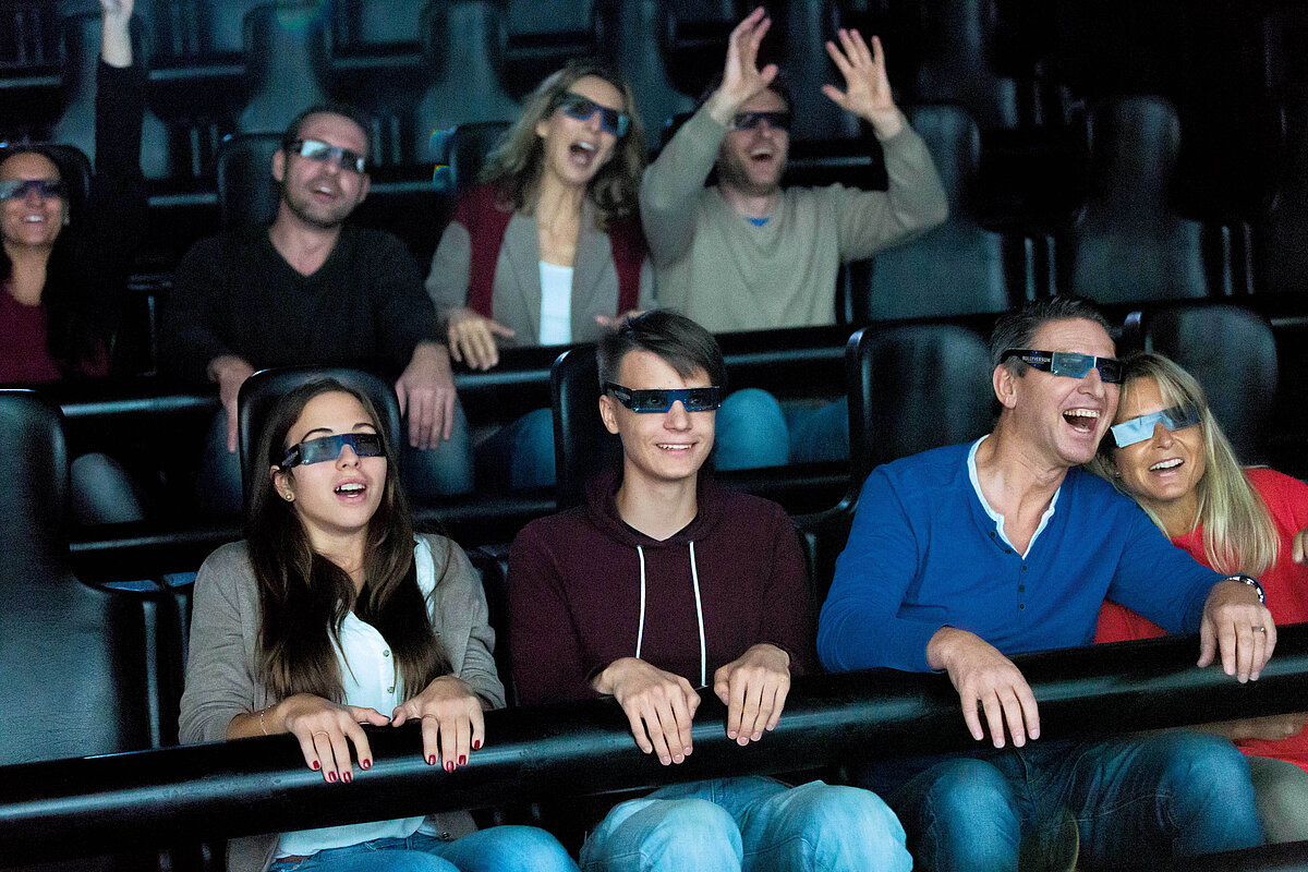Besucher sitzen im 4D-Kino mit entsprechenden Brillen auf dem Kopf