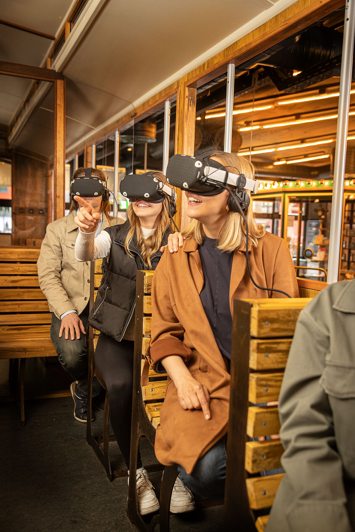 Gäste im Nachbau einer alten Tram, die VR-Brillen auf dem Kopf haben.